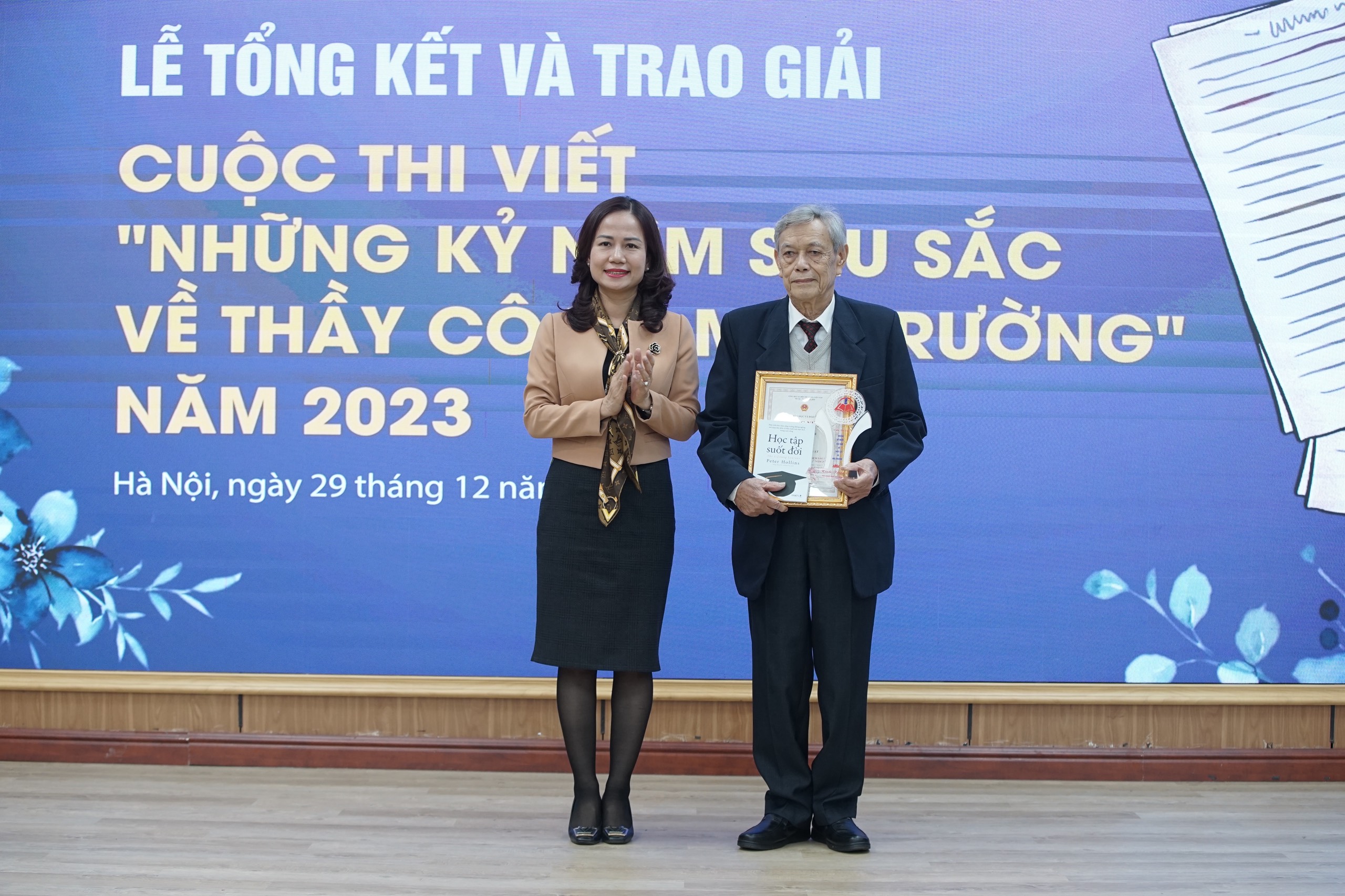 Bà Vương Hương Giang - Phó Giám đốc Sở GD&amp;ĐT Hà Nội trao giải nhân vật cho thầy giáo Trần Thọ Đổng, nguyên Hiệu trưởng Trường THPT Nghi Lộc 3.