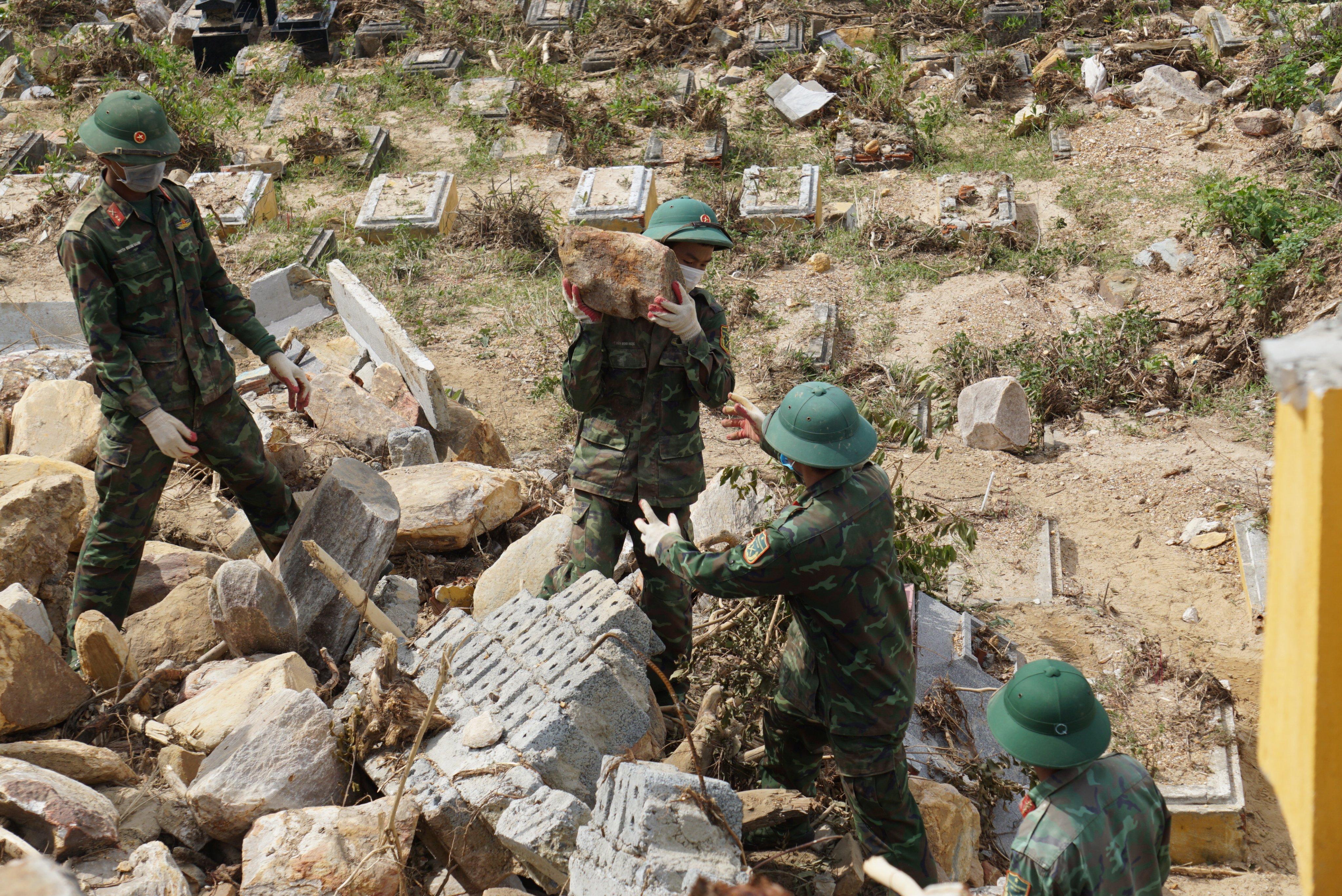 Bộ đội đang vác đá để tìm kiếm những ngôi mộ bị vùi lấp sau cơn lũ ở nghĩa trang Hòa Sơn TP. Đà Nẵng. 