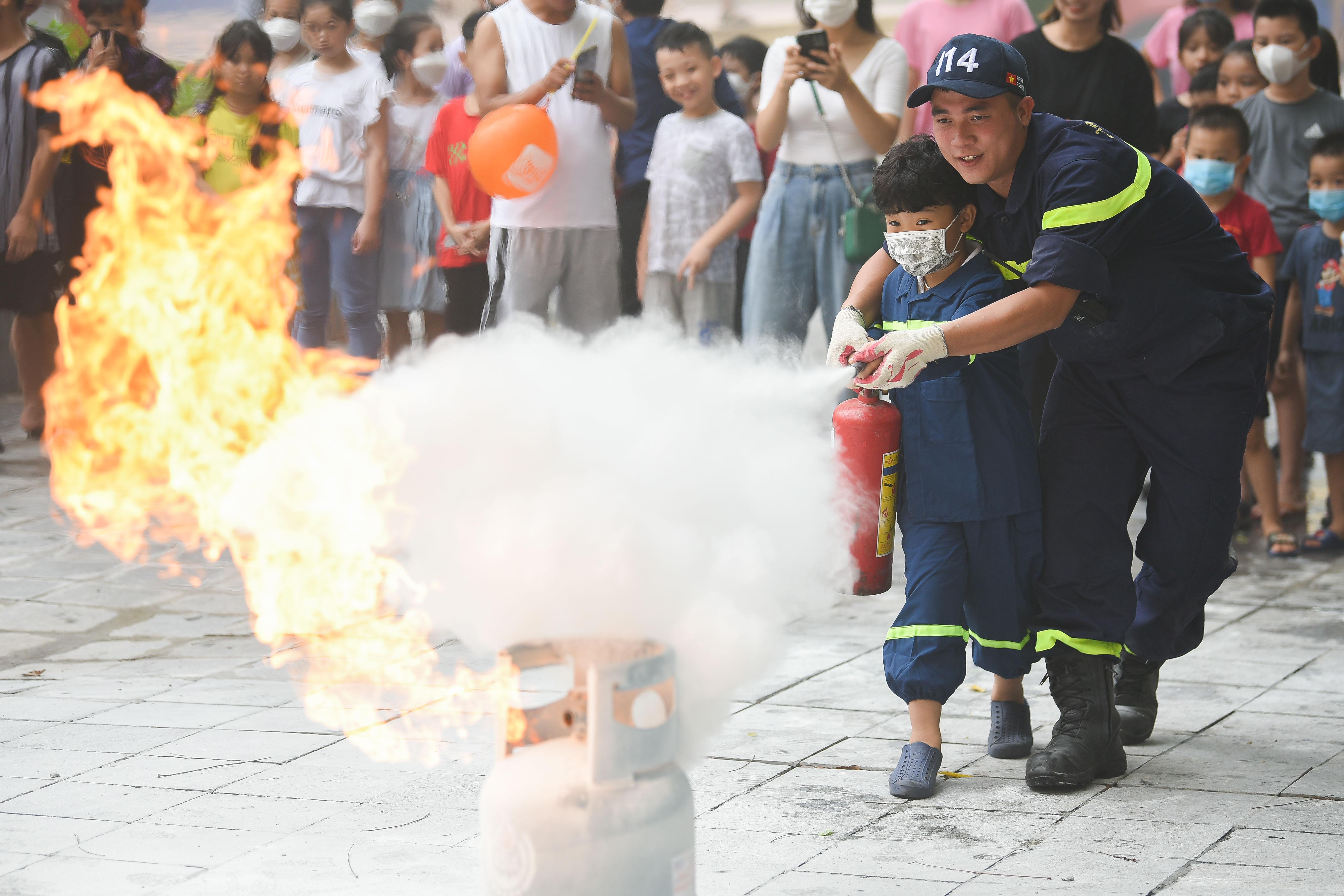 Học sinh được hướng dẫn sử dụng bình chữa cháy để dập tắt đám cháy.