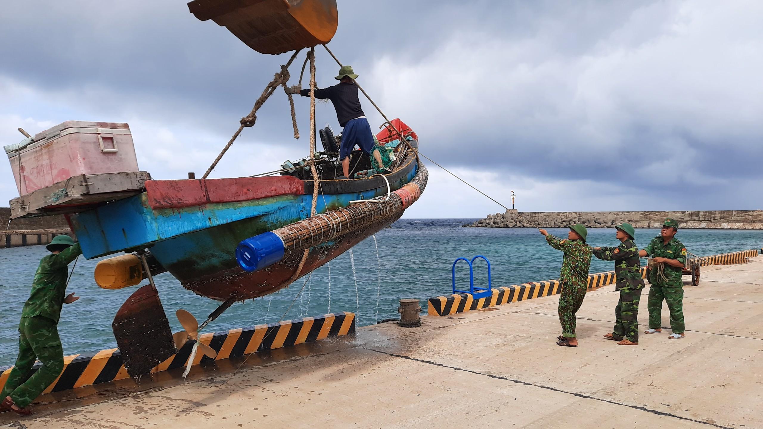Lực lượng vũ trang Quảng Trị hỗ trợ người dân cẩu thuyền lên bờ tránh bão.