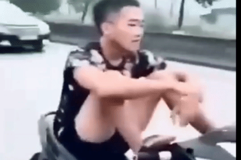 Nam thanh niên đầu trần, dùng chân lái xe trên đường khiến người xem bức xúc. (Ảnh cắt từ clip)