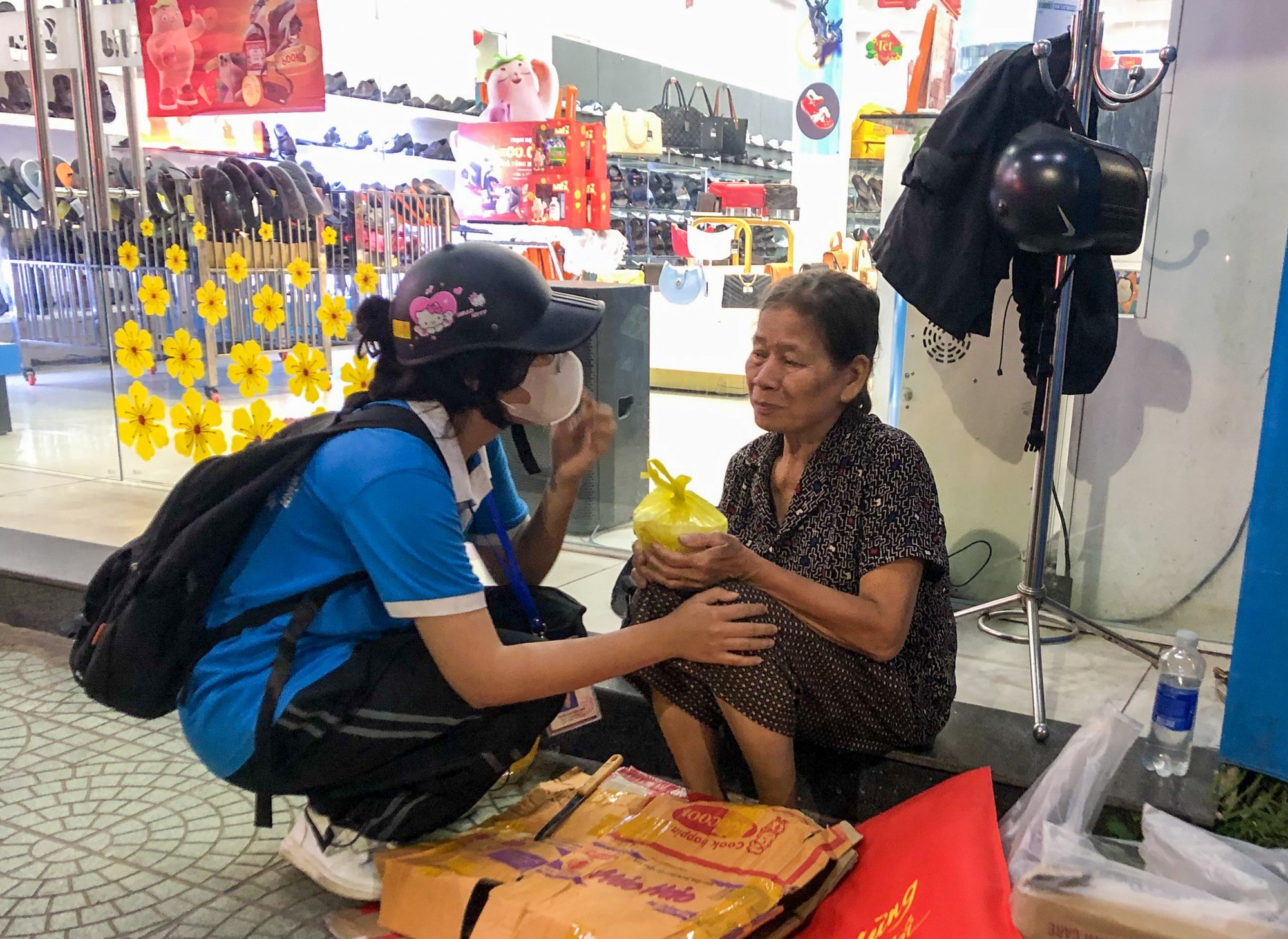 Ân cần hỏi thăm và gửi phần cháo cho một cụ bà vô gia cư trước Nhà sách Phú Xuân tại đường Trần Hưng Đạo, TP Huế.