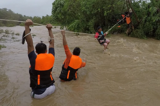Nhân viên cứu hộ sơ tán người dân ở gần một con sông tràn bờ.