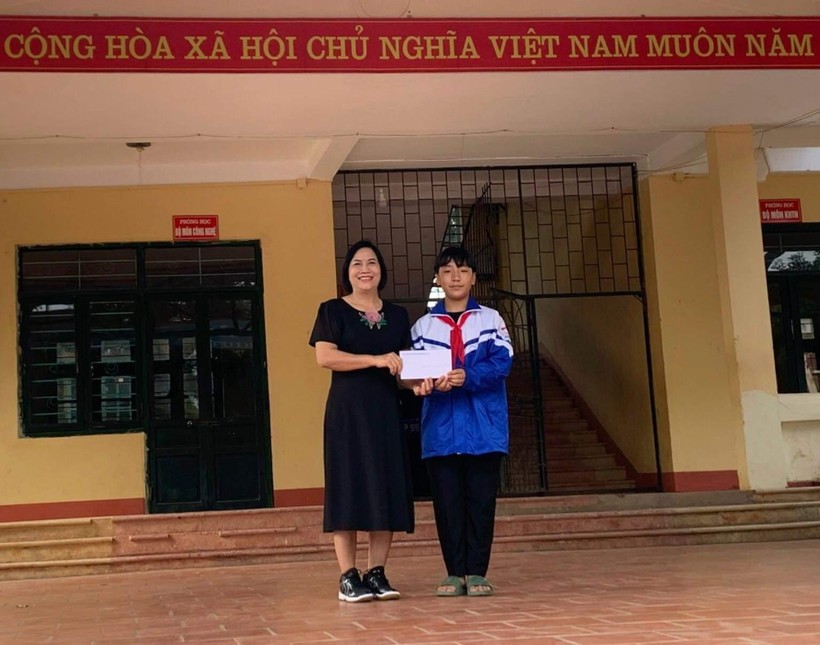 Cô giáo Ngô Thị Hường, Hiệu trưởng trường THCS thị trấn Hương Sơn, huyện Phú Bình trao quà động viên khen thưởng cho em Nguyễn Quang Minh, học sinh lớp 9D.