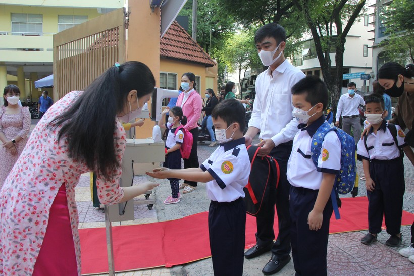 Học sinh Trường Tiểu học Nguyễn Bỉnh Khiêm (Quận 1) đo thân nhiệt và rửa tay sát khuẩn trước khi vào trường.