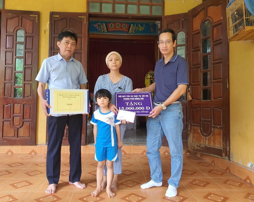 Ông Đào Anh Dũng và ông Đặng Ngọc Hùng đại diện cho Đội Quy tắc trật tự và đô thị thành phố Đồng Hới trao tặng quà và số tiền 15 triệu đồng động viên đến gia đình cô Đỗ Thị Phương Nhi.