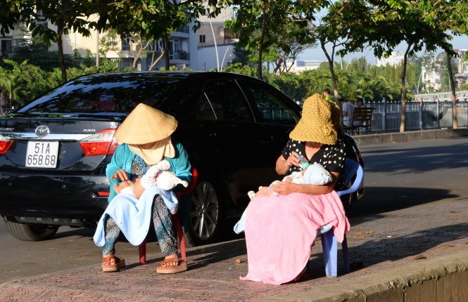 Hai phụ nữ tắm nắng cho trẻ sơ sinh trên đường Trường Sa, Q.Bình Thạnh (TP.HCM) - Ảnh: Hữu KHoa
