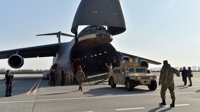 Quân nhân Mỹ đưa xe bọc thép xuống máy bay ở sân bay Kiev. Ảnh: AFP 