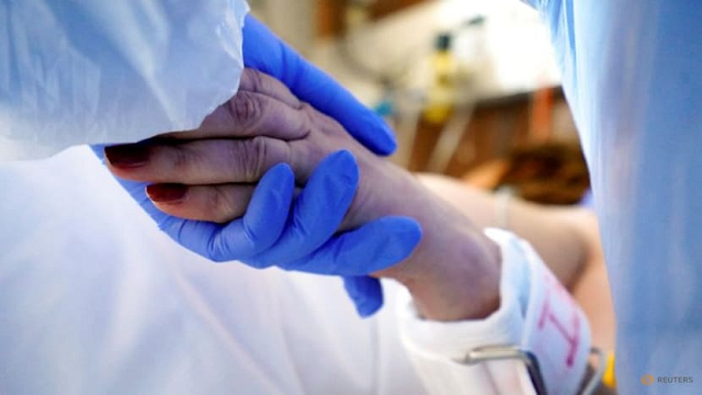 Nhân viên y tế nắm tay bệnh nhân Covid-19 tại một bệnh viện ở Latvia - nơi số ca tử vong tăng mạnh.
