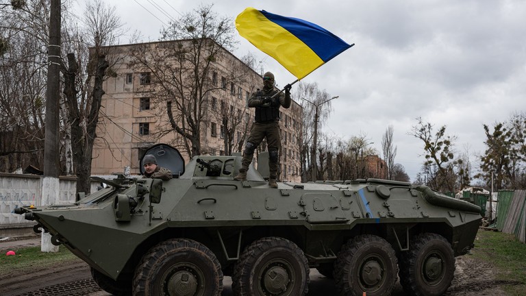 Binh sĩ Ukraine vẫy quốc kỳ khi đứng trên nóc xe bọc thép chở quân (APC). )Ảnh: Alexey Furman / Getty Images)
