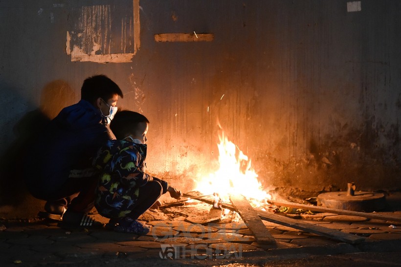 Nền nhiệt độ về đêm tại Hà Nội xuống dưới 12 độ C, nhiều người làm việc ngoài trời đã đốt lửa để sưởi ấm.