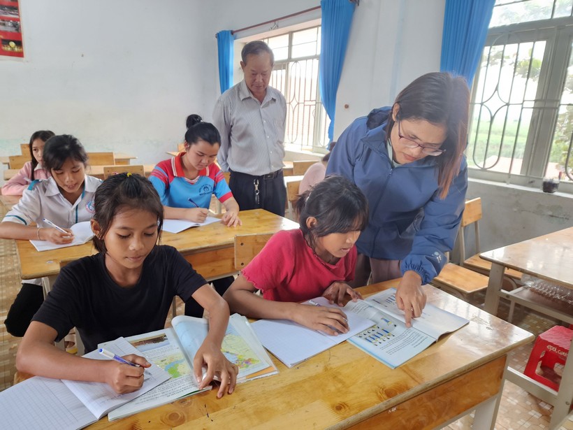 Thầy Nguyễn Hải Hoán (người đứng hàng sau) kiểm tra 1 lớp phổ cập giáo dục gồm nhiều độ tuổi cho học sinh xã Cư Prao. (Ảnh: Thành Tâm)