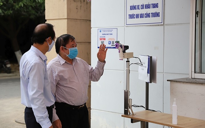 GS.TSKH Bùi Văn Ga (bên phải) kiểm tra máy đo thân nhiệt từ xa tại Trường Đại học Ngoại ngữ -Đại học Đà Nẵng.