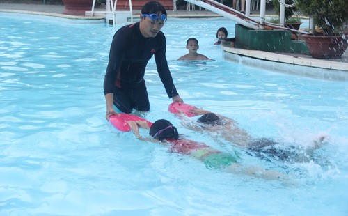 Thầy Phan Hữu Quý đang dạy bơi cho 2 em học sinh tiểu học