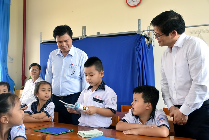 Thứ trưởng Nguyễn Hữu Độ (trái) và Vụ trưởng Vụ GD Tiểu học Thái Văn Tài nghe một học sinh lớp 1 tại Trường Tiểu học Võ Thị Sáu (TP Tân An, Long An) đánh vần.