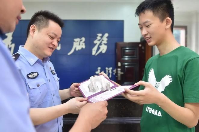 Wu Jinlin (phải) khoe thư mời nhập học với các sĩ quan cảnh sát.