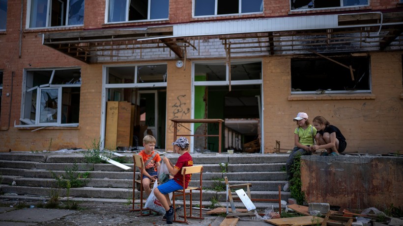 Trẻ em Ukraine vui chơi bên ngoài một tòa nhà bị phá hủy. Ảnh: INT