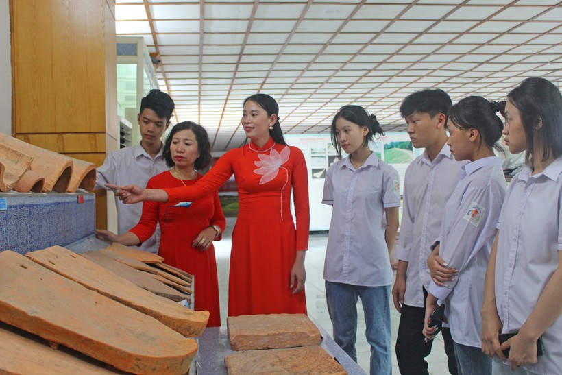 Cô Lan Anh (thứ 2 từ trái qua) cùng học trò nghe hướng dẫn viên giới thiệu về hiện vật được trưng bày tại Thành Nhà Hồ.