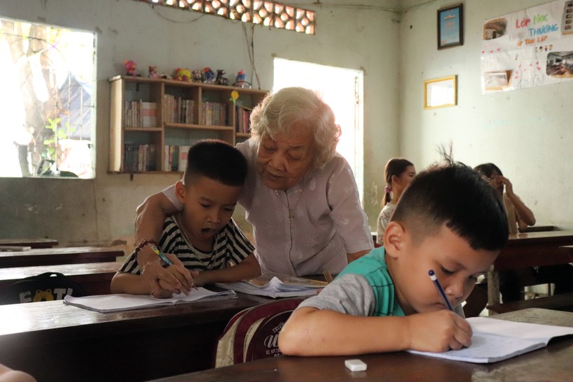Bà Tư cầm tay dạy trẻ viết chữ. Ảnh: Bùi Vân