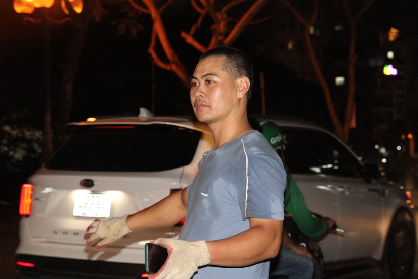 Anh Phạm Văn Hiếu dùng đèn flash điện thoại cảnh báo cho phương tiện tham gia giao thông tại đoạn đường nhóm đang sửa chữa.