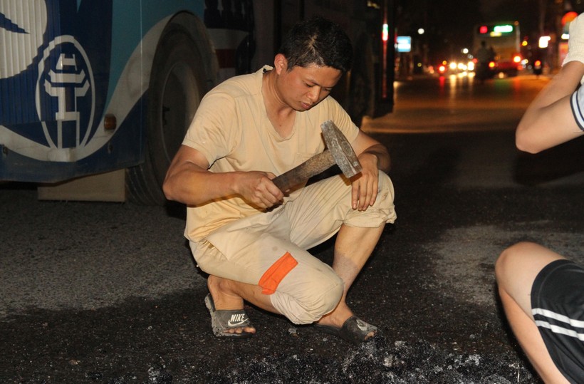 Anh Lê Văn Dũng dùng búa đập nhỏ những nguyên vật liệu để vá một 'ổ gà' tiềm ẩn nguy hiểm trên đường Tam Trinh.