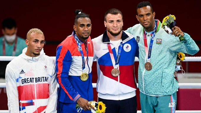 Ben Whittaker (trái) vẻ mặt không cảm xúc khi đứng cùng nhóm nhận Huy chương Olympic.