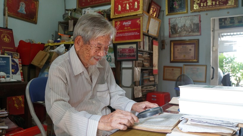 Nhà nghiên cứu Nguyễn Đình Tư dùng kính lúp, xem tài liệu tại nhà riêng. Ảnh: Mạnh Tùng