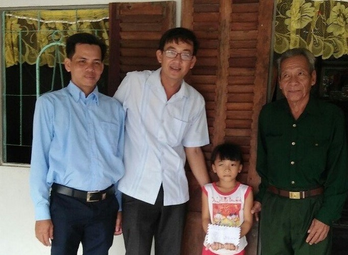 Thầy Giang (thứ 2 từ trái qua) cùng học viên lớp H97 tặng quà cho HS nghèo và gia đình có công với Cách mạng