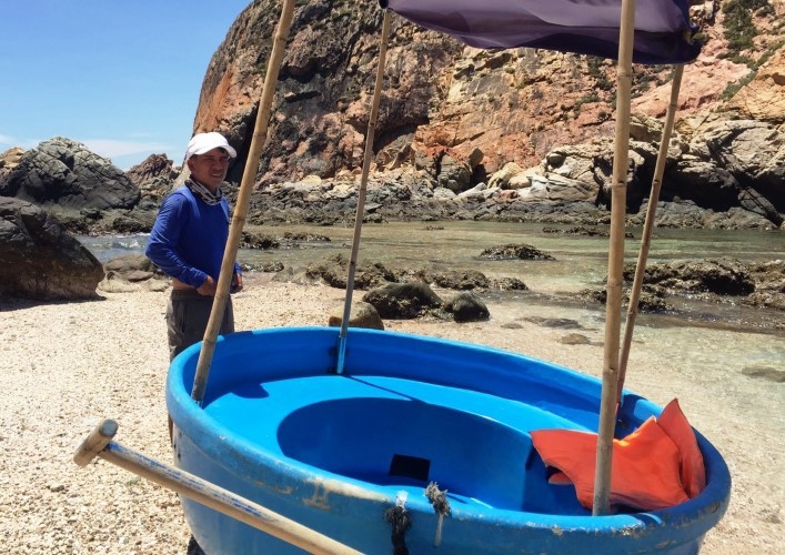 Anh Bùi Ngọc Quang trầm tư bên chiếc thuyền thúng làm dịch vụ ngắm san hô.