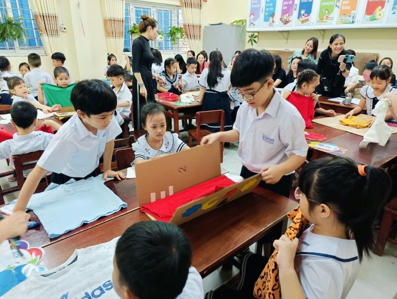 Học sinh lớp 1/1, Trường Tiểu học Lê Lai (quận Hải Châu, TP Đà Nẵng) thực hành gấp quần áo từ dụng cụ tự thiết kế qua bài học STEM. Ảnh: Hà Nguyên