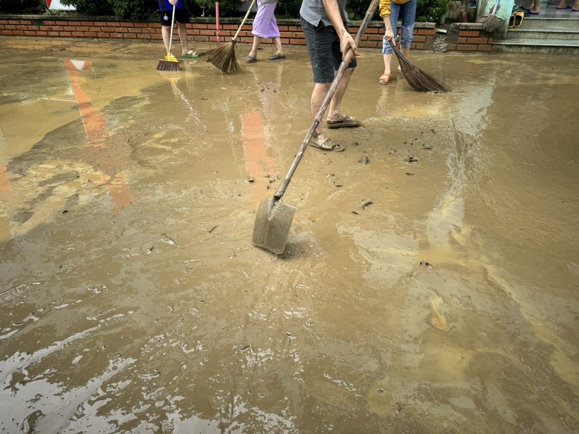 Sân trường Tiểu học Hồng Quang đóng một lớp bùn dày sau khi nước rút. ảnh 1