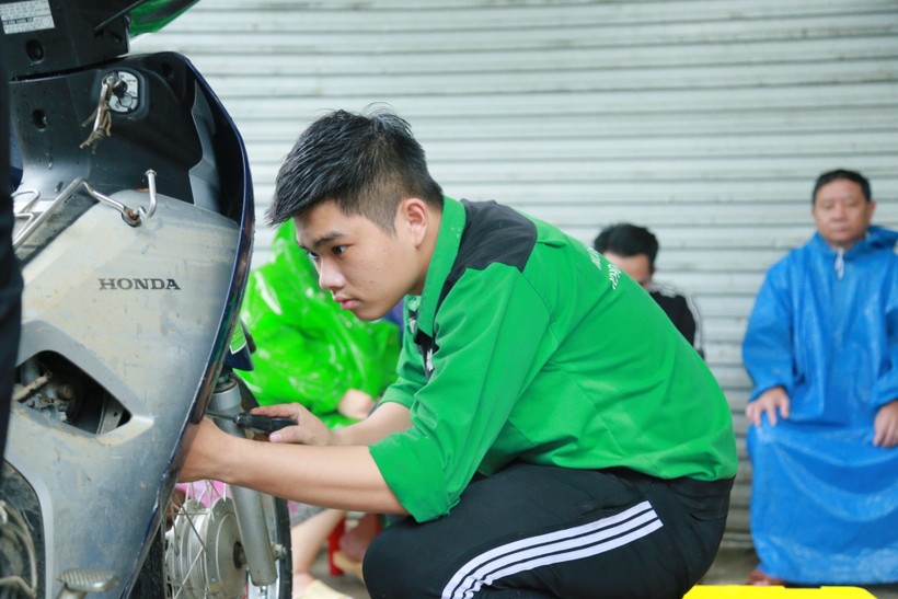 Thành viên của đội SOS tham gia sửa xe máy bị ngập nước cho người dân khu vực đường mẹ Suốt đều là sinh viên thuộc khối Kỹ thuật của Trường ĐH Đông Á. ảnh 1