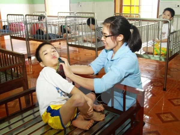 Giáo viên chăm sóc cho trẻ khuyết tật. (Ảnh: Doãn Tấn/TTXVN)