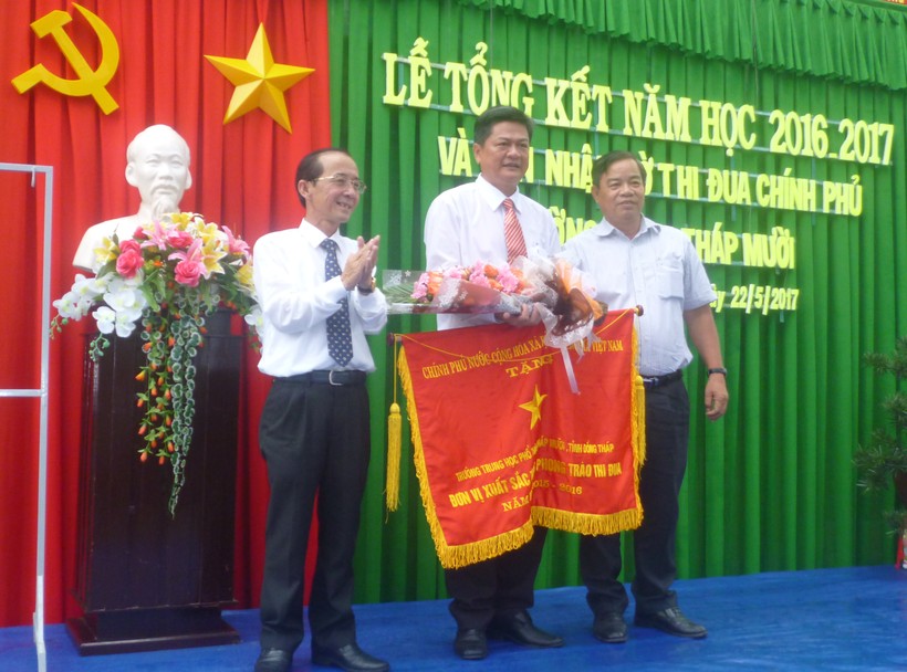 Thầy Nguyễn Văn Định (giữa), thay mặt tập thể Trường THPT Tháp Mười nhân Cờ thi đua Chính phủ