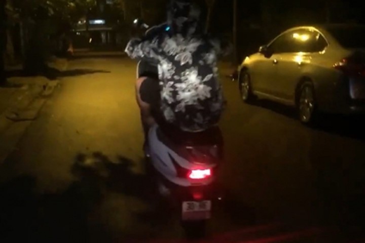 Một nam thanh niên mặc áo chống nắng biểu diễn màn bốc đầu chiếc xe tay ga gây náo loạn đường phố đêm khuya.