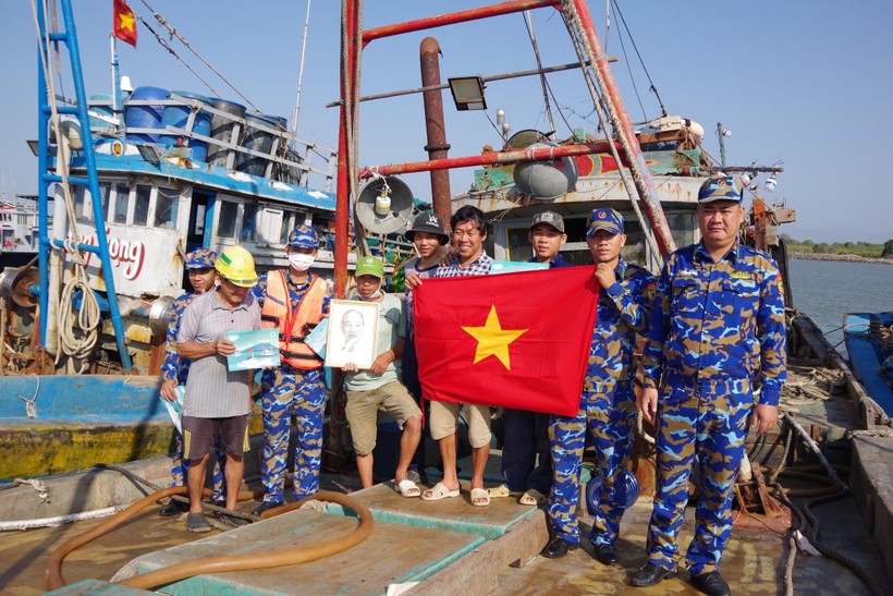 Cán bộ đội tuyên truyền trao tặng cờ Tổ quốc, ảnh Bác Hồ và phát tờ rơi tuyên truyền cho ngư dân.