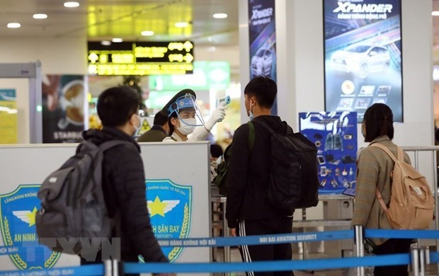 Nhân viên an ninh hàng không tại sân bay Nội Bài kiểm tra thân nhiệt của hành khách. (Ảnh: Huy Hùng/TTXVN).