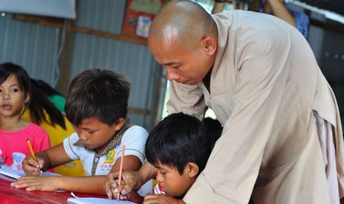 Thầy Chơn Nguyên đang hướng dẫn các em nhỏ tập viết 
