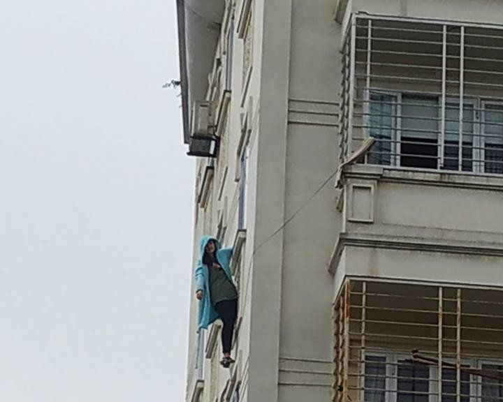 Hình ảnh cô gái đu mình vắt vẻo trên cửa sồ tầng 4 của một một chung cư trên phố Nguyên Hồng.