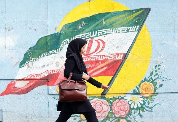 Một người phụ nữ đi qua một bức tranh cổ động về tinh thần yêu nước trên đường phố Tehran
