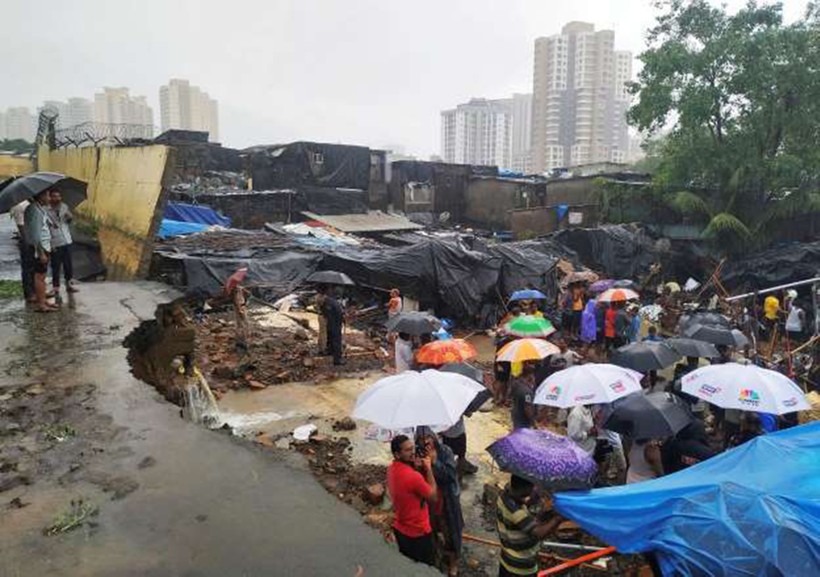 Người dân đứng giữa đống đổ nát sau khi một bức tường sụp đổ do mưa lớn ở Mumbai