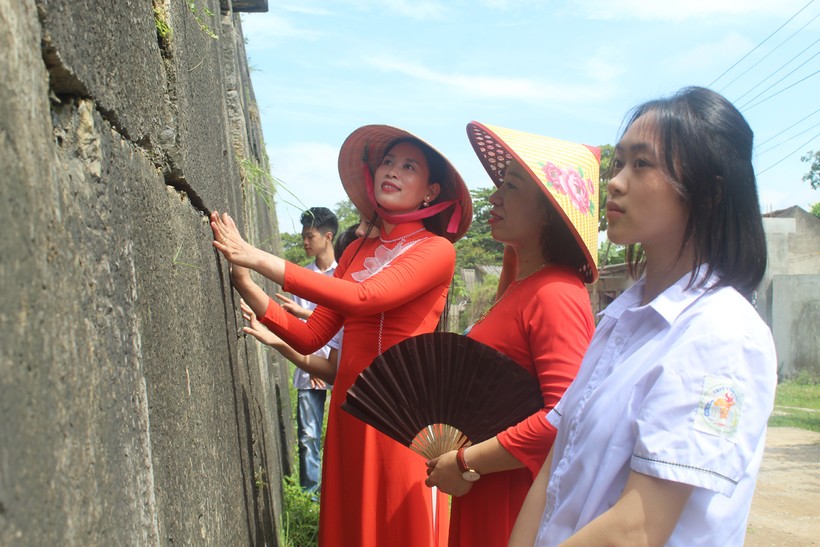 Cô Quách Lan Anh (áo đỏ từ phải qua) cùng học sinh nghe hướng dẫn viên giới thiệu về kiến trúc tường Thành nhà Hồ. Ảnh: LT. ảnh 2