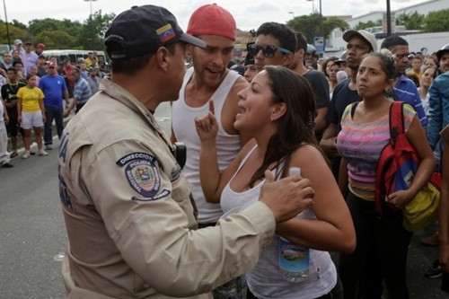 Một phụ nữ hôm 14/6 tranh cãi với cảnh sát chống bạo động trong cuộc biểu tình về tình trạng thiếu lương thực ở Caracas. Ảnh: Reuters
