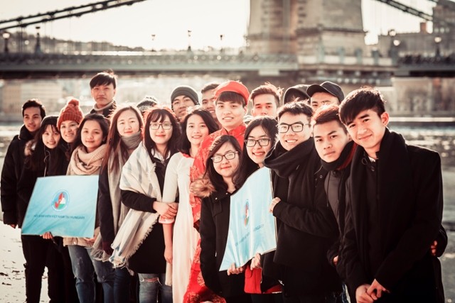 Nguyễn Đình Cường mặc áo dài đỏ chụp ảnh cùng các bạn.