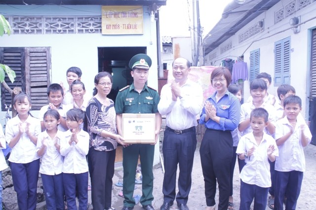 Ông Nguyễn Đình Tâm - TGĐ Tập đoàn Thiên Long và Đại diện Trung Ương Hội LHTN VN trao quà cho lớp học tình thương của thầy giáo Lê Văn Cường (người mặc quân phục).