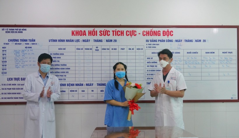 Bác sĩ Lê Đức Nhân (bìa phải) - Giám đốc bệnh viện Đà Nẵng và bác sĩ Nguyễn Thành Trung (bìa trái - PGĐ Bệnh viện tặng hoa cho nữ điều dưỡng. 
