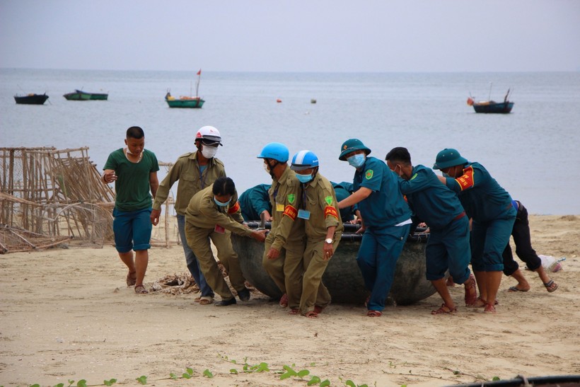Lực lượng dân phòng cùng dân quân tự vệ hỗ trợ di chuyển thuyền thúng của người dân lên bờ. 