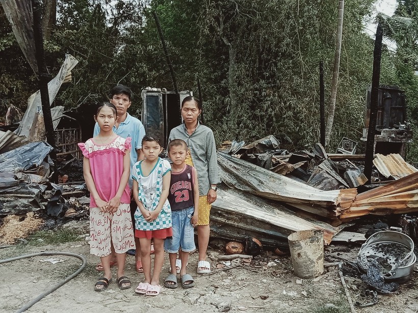 Gia đình anh Hộ Mai Hữu Toàn bên căn nhà bị cháy.