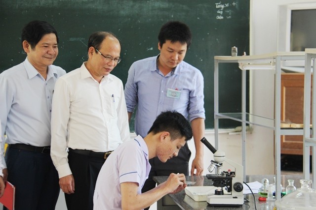 Ông Nguyễn Quốc Anh, Phó giám đốc Sở GD&ĐT (bên trái, thứ 2) theo dõi phần thi thực hành môn Hóa của một thí sinh. 