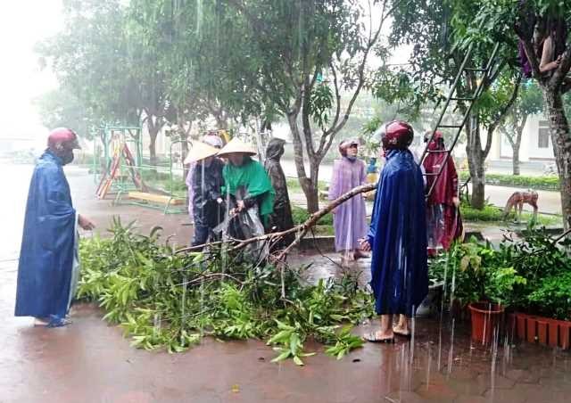Giáo viên đội mưa chặt tỉa cành cây ở Trường MN Thượng Lộc (Can Lộc).